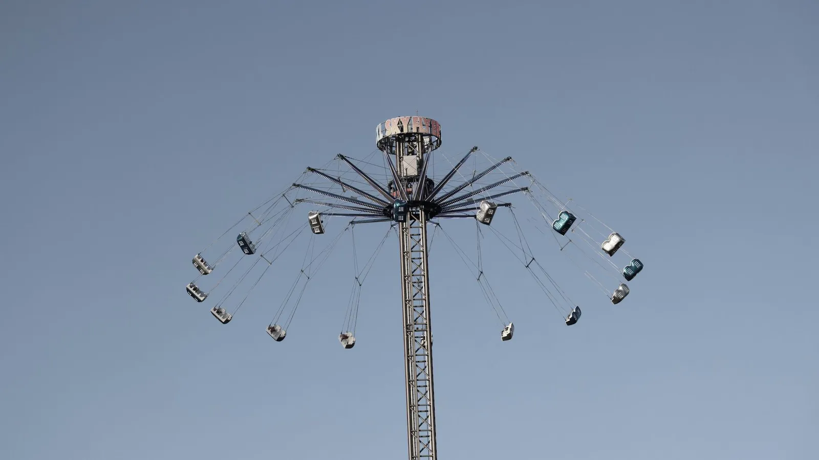High swing ride in motion at amusement park against a clear sky.