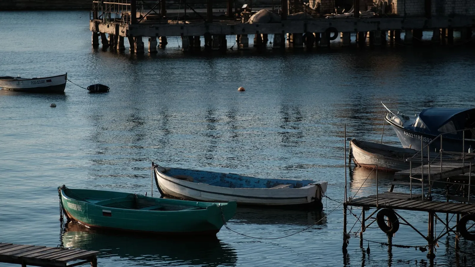 A tranquil image of boats gently floating on water at a docking area during dusk, capturing a peaceful evening mood.