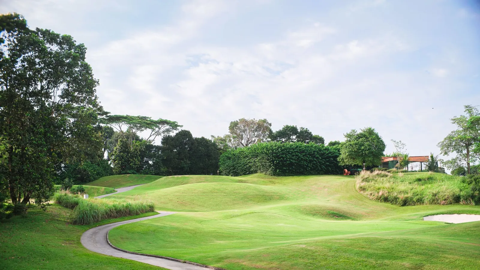 Scenic view of a vibrant golf course with manicured lawns, trees, and a clear blue sky.