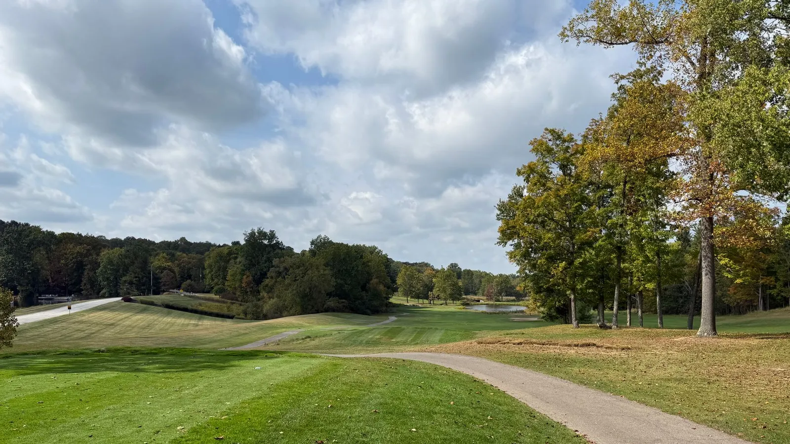 Beautiful golf course with lush greens and fall foliage under a partly cloudy sky.