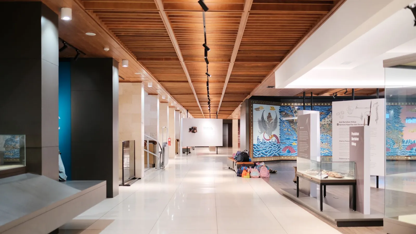 Bright museum hallway with exhibits and empty walkways, showcasing modern design.