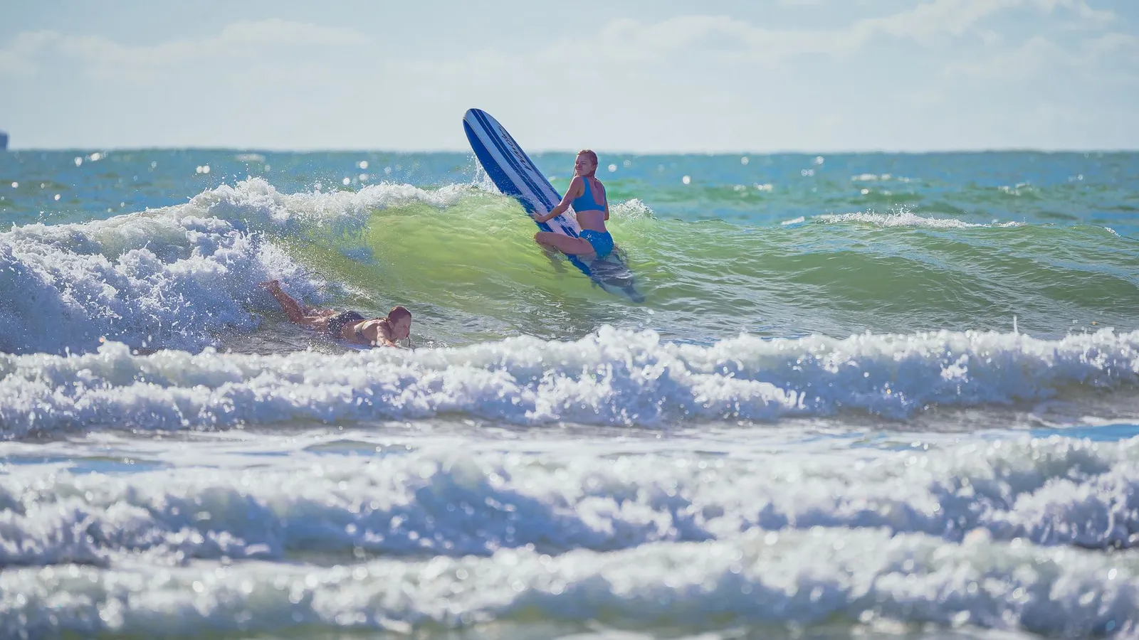 Exciting surfing action with women riding waves under the bright sky. Perfect for leisure and water sports scenes.