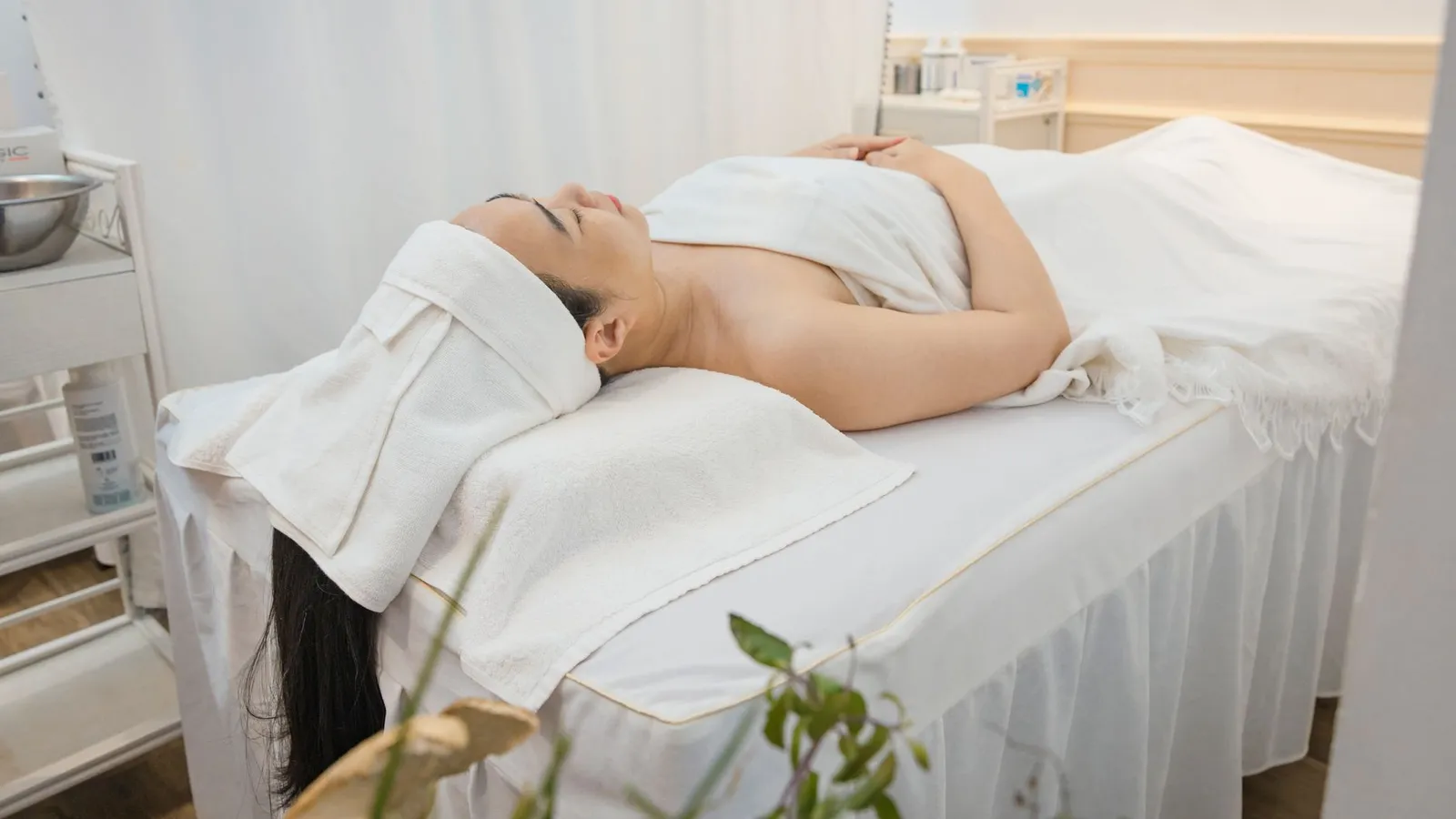 Woman enjoying a calming spa treatment indoors, wrapped in towels for ultimate relaxation.